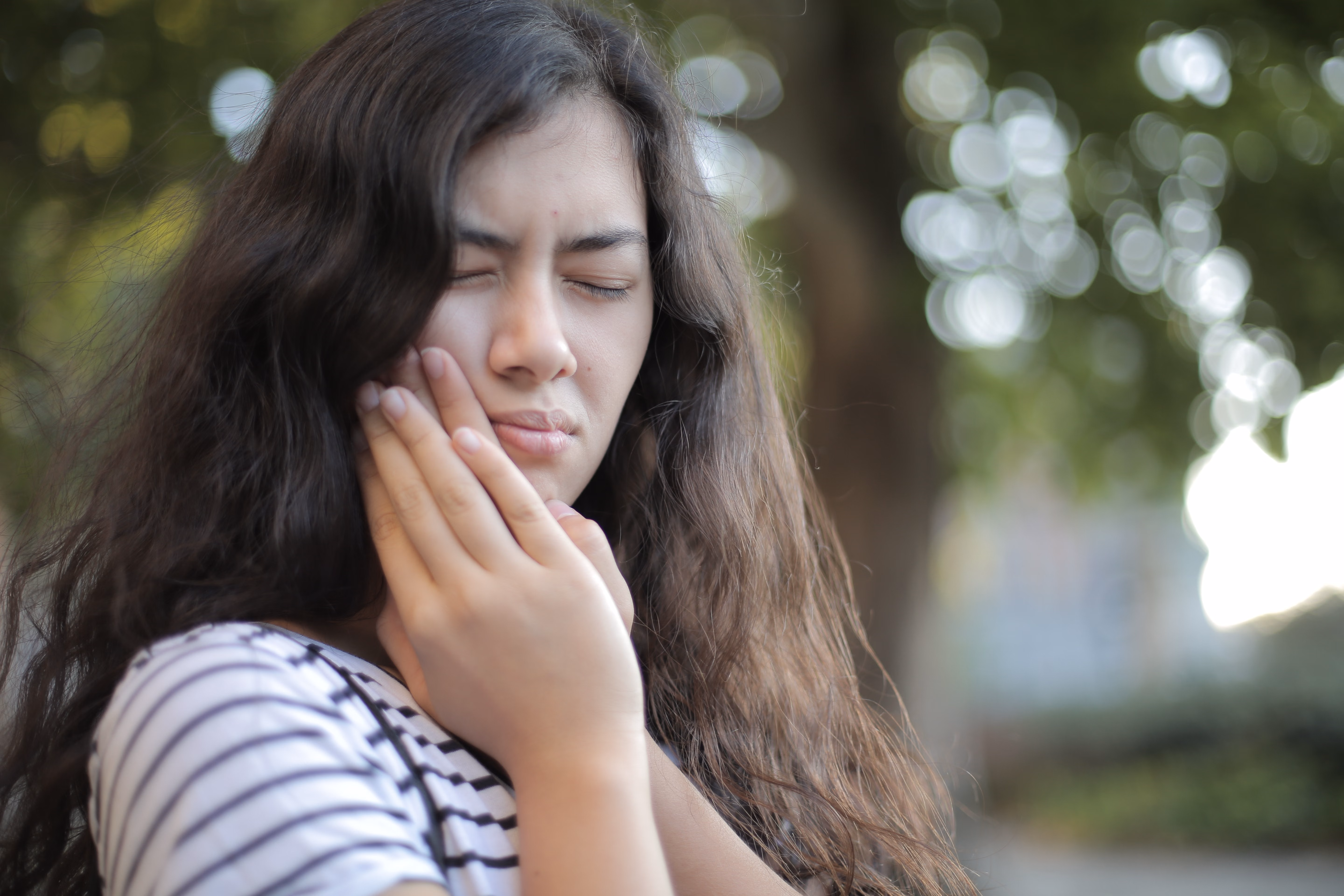Young woman holding her cheek in pain from a toothache