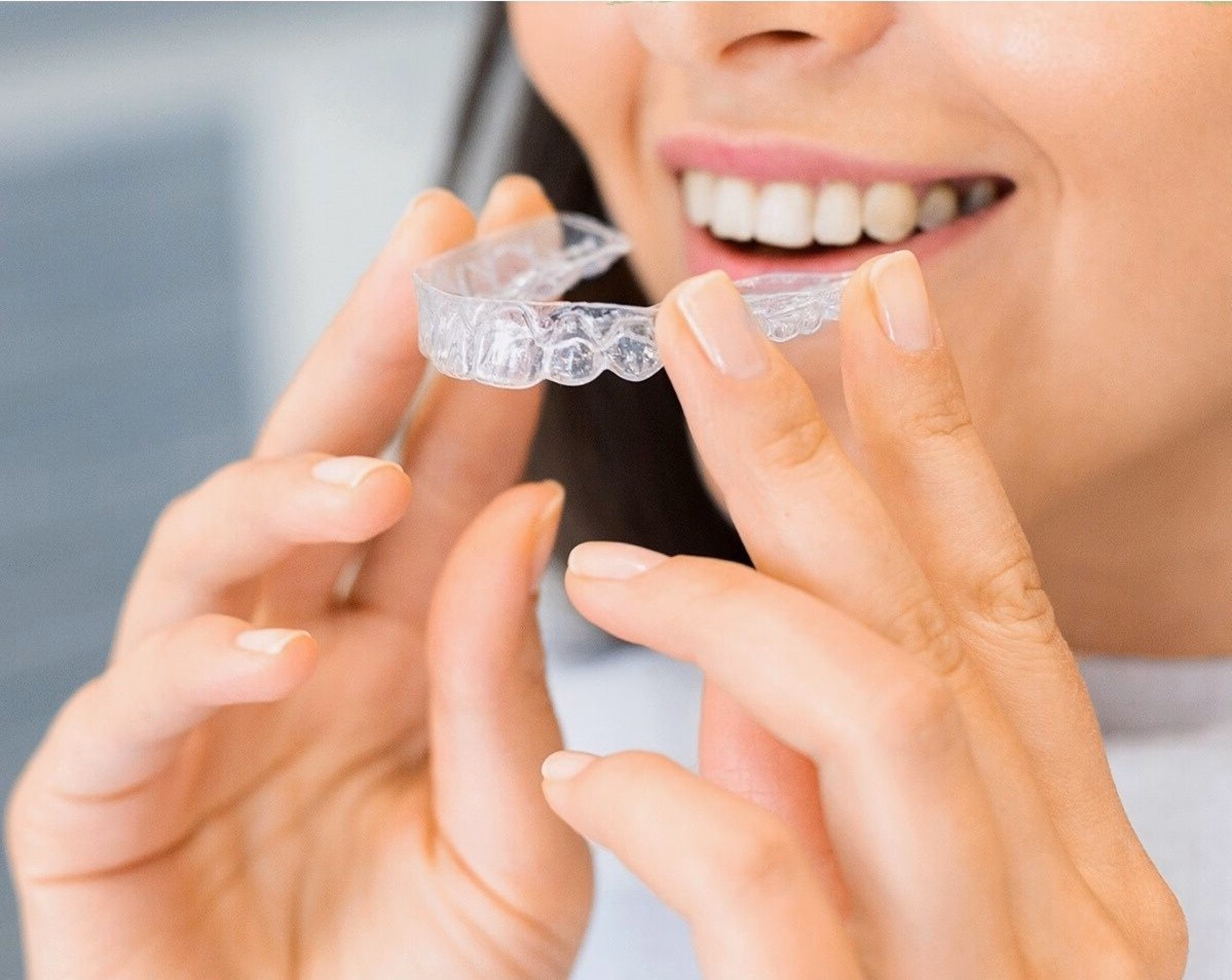Smiling woman holding a clear aligner