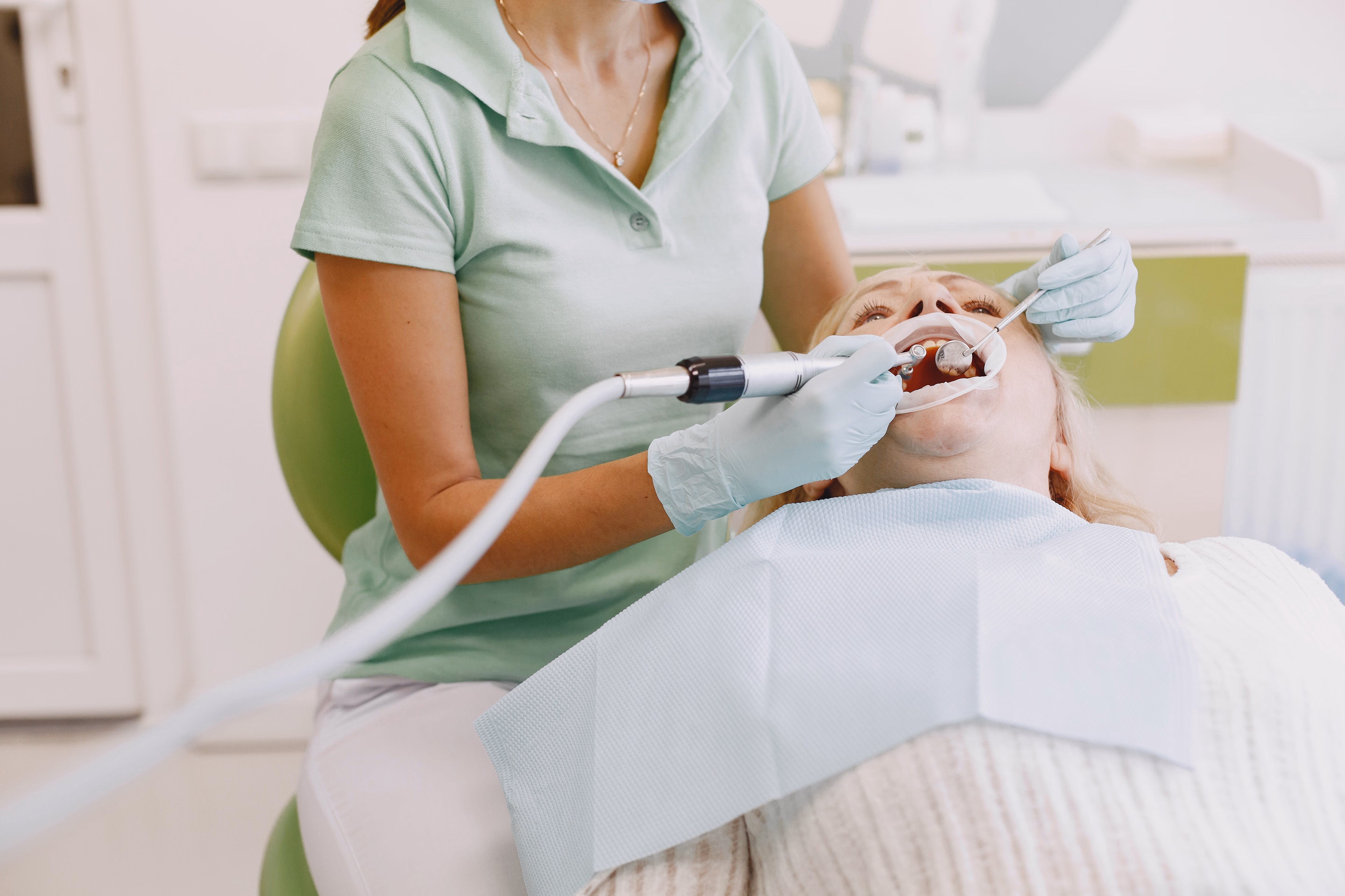 Dental hygienist cleaning a patient's teeth in the dental chair
